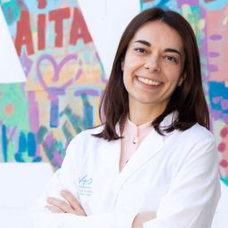 La Dra, Eva Muñoz Cosuelo con bata VHIO en una pared con letras de colores